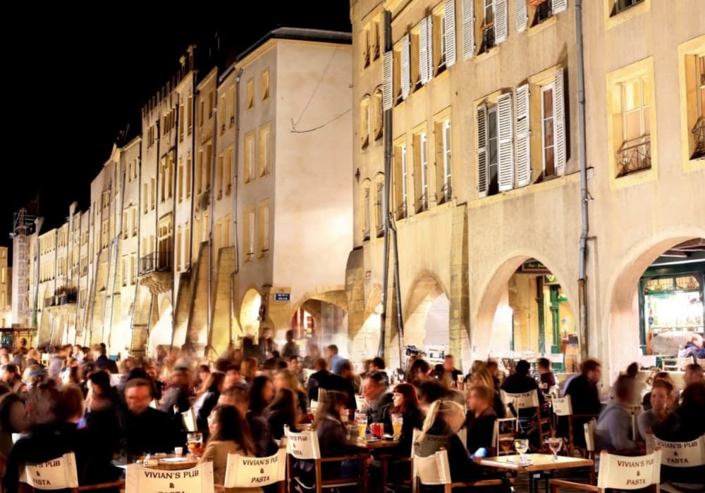 Terrasse animée sur la place Saint-Louis à Metz avec des bars à vin