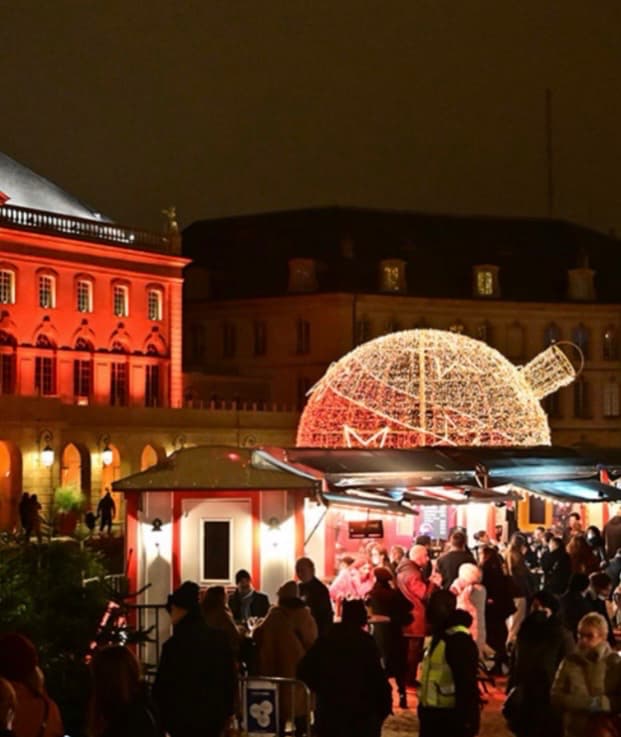 Boule de Noël géante et scintillante sur la place de la Comédie devant l'Opéra-Théâtre de Metz illuminé en rouge.