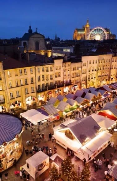 Vue panoramique du marché de Noël de la place Saint-Louis à Metz avec ses chalets illuminés, le carrousel et la grande roue.