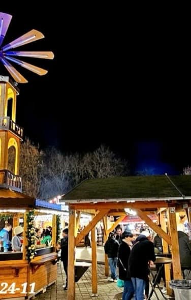Carrousel traditionnel illuminé à côté d'une haute pyramide de Noël en bois sur une place pavée à Metz sous un ciel de nuit