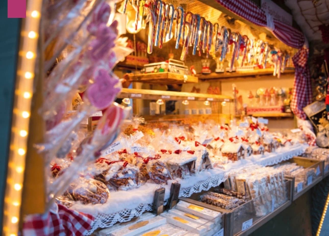 Étalage de confiseries, bonbons et sucres d'orge suspendus dans un chalet en bois sur un marché de Noël